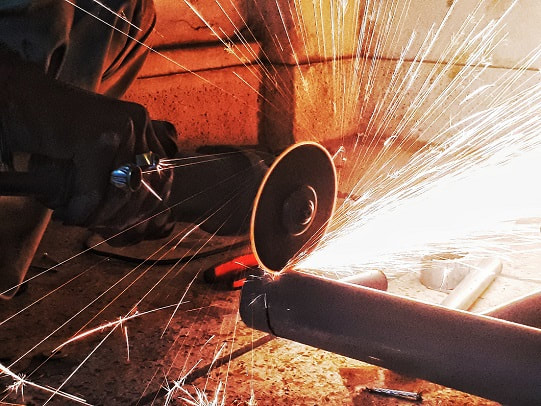 Angle grinder cutting a metal pipe