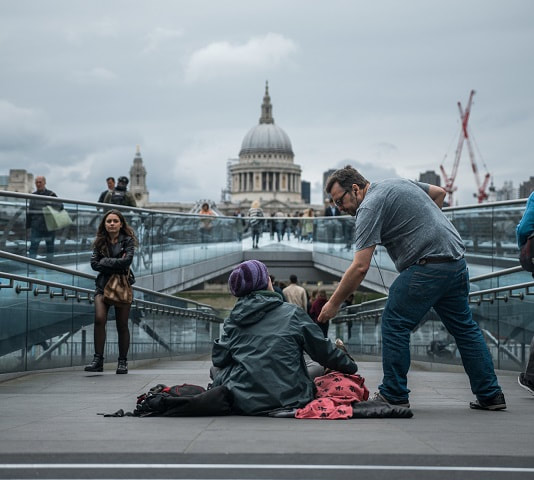 A man giving a homeless man  some money